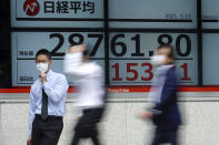 A man wearing a protective mask stands in front of an electronic stock board showing Japan's Nikkei 225 index at a securities firm Wednesday, May 12, 2021, in Tokyo. Asian stock markets retreated Wednesday as investors looked ahead to U.S. data they worry will show inflation is picking up. (AP Photo/Eugene Hoshiko)