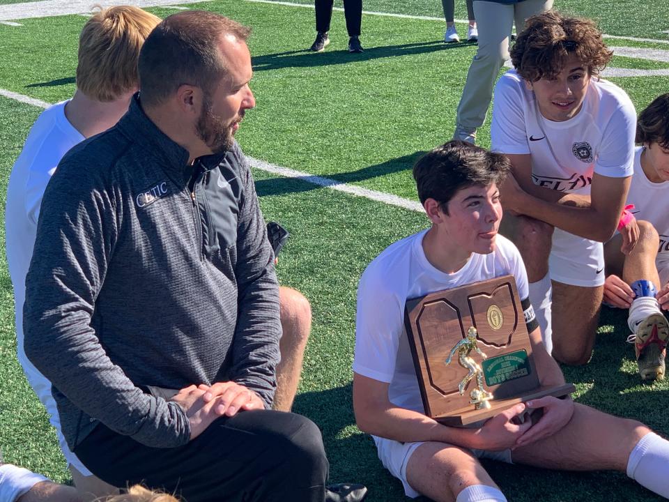 Senior midfielder Joseph Bender holds the championship trophy Nov. 6 as Dublin Jerome boys soccer coach Nate Maust talks to the team after beating New Albany 1-0 in a Division I regional final at DeSales.