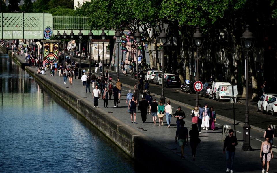 People walk along the Ourc canal during a sunny Sunday in Paris, despite a strict lockdown - Philippe LOPEZ / AFP