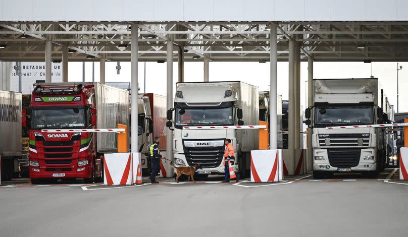 An employee of Eurotunnel and his dog check trucks on their way to Great Britain at the exit of the Channel tunnel in Calais