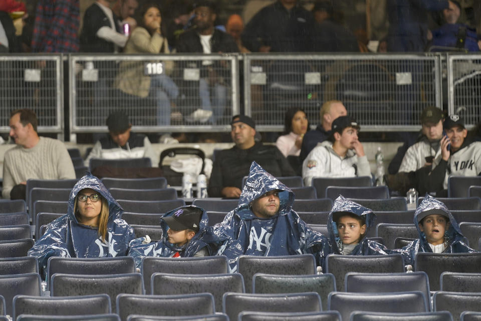 Baseball fans wait out a rain delay for Game 5 of an American League Division baseball series between the New York Yankees and the Cleveland Guardians, Monday, Oct. 17, 2022, in New York. (AP Photo/Seth Wenig)