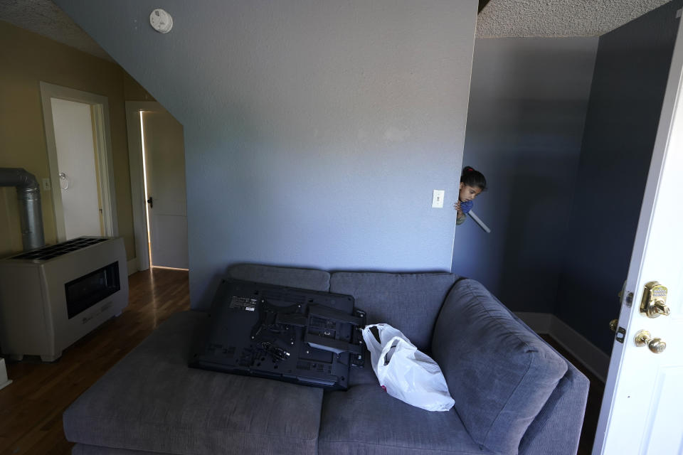 One of the four children of Abdul (not shown), who worked as a mechanic before he left Kabul, Afghanistan with his family about a month ago, peers out from a staircase, Thursday, Sept. 16, 2021, in the rental house the family has been provided as a place to stay in Seattle. The home is owned by Thuy Do, who was nine years old when her family arrived in the United States from Vietnam in the 1980s. Now Do and her husband have offered their vacant rental home to refugee resettlement groups to house newly arriving Afghans in need of a place to stay. (AP Photo/Ted S. Warren)