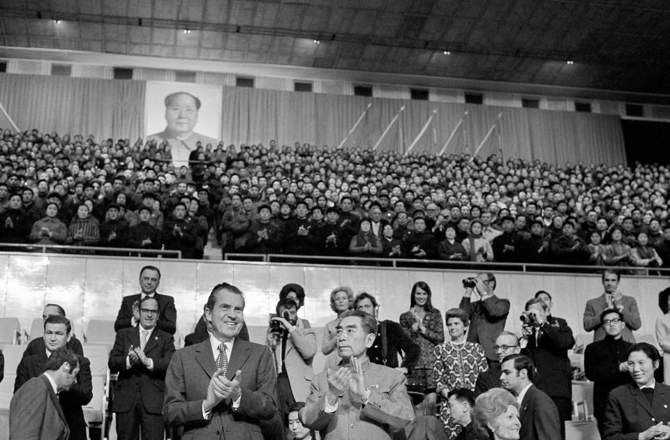 FILE - Then U.S. President Richard Nixon and then China's Premier Zhou Enlai join the applause at a gymnastic show in Beijing on Feb. 23, 1972 as they stand in the official box under a capacity crowd with a portrait of Chairman Mao Zedong above. First Lady Pat Nixon is seated on lower right. At the height of the Cold War, U.S. President Richard Nixon flew into communist China's center of power for a visit that over time would transform U.S.-China relations and China's position in the world in ways that were unimaginable at the time. (AP Photo, File)