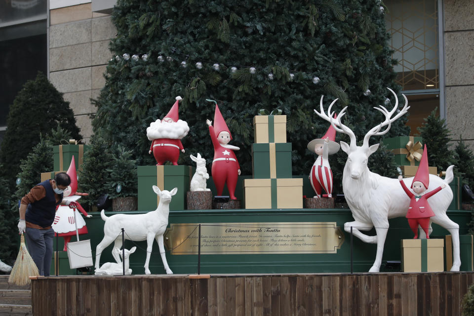 A man wearing a face mask as a precaution against the coronavirus, sweeps with a broom near Christmas decoration in downtown Seoul, South Korea, Thursday, Nov. 26, 2020. (AP Photo/Lee Jin-man)