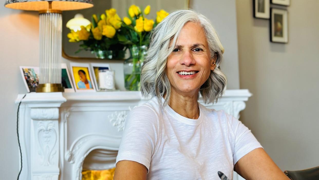 Woman with grey hair and a white tee smiling