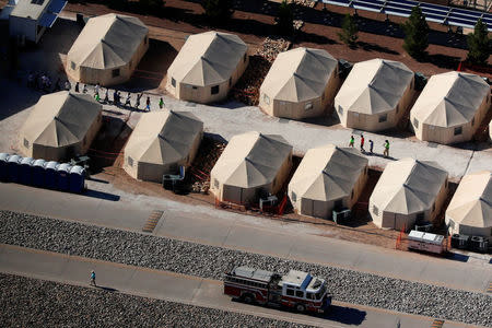 Immigrant children, many of whom have been separated from their parents under a new "zero tolerance" policy by the Trump administration, are shown walking in single file between tents in their compound next to the Mexican border in Tornillo, Texas, U.S. June 18, 2018. REUTERS/Mike Blake