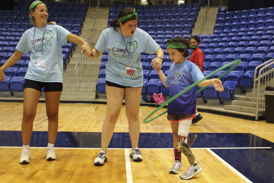 Anya Rhodes, 8, of Newton Mass., right, plays a game with a hula hoop during Camp No Limits, Friday, July 14, 2023 at Quinnipiac University in Hamden, Conn. Camp No Limits is helping train students at Quinnipiac University with a four-day program, run and staffed by students in the university's physical and occupational therapy program on the school's campus. (AP Photo/Pat Eaton-Robb)