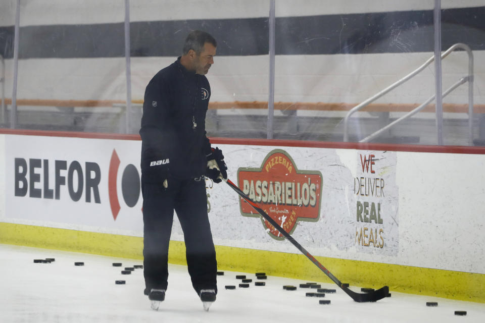 Philadelphia Flyers head coach Alain Vigneault gathers pucks during training camp at the NHL hockey team's practice facility Monday, July 13, 2020, in Voorhees, N.J. (AP Photo/Matt Slocum)