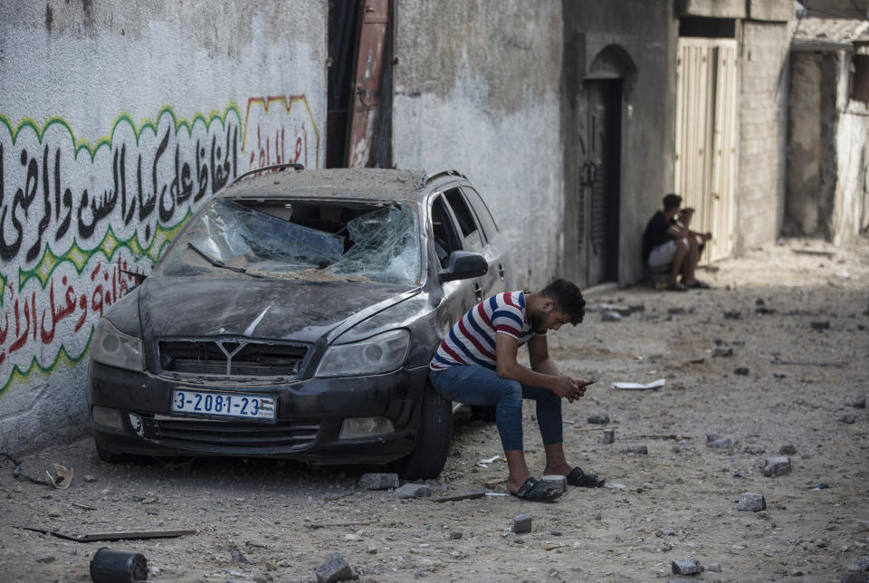 A Palestinian man sits on a damaged car following Israeli airstrikes on Jabaliya refugee camp, northern Gaza Strip, Thursday, May 20, 2021. Heavy airstrikes pummeled a street in the Jabaliya refugee camp in northern Gaza, destroying ramshackle homes with corrugated metal roofs nearby. The military said it struck two underground launchers in the camp used to fire rockets at Tel Aviv. (AP Photo/Khalil Hamra)