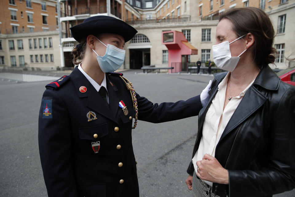 French math teacher-volunteer fighter, Marion Dehecq, left, talks with Paris-based Associated Press journalist Lori Hinnant, after she receives a bronze medal for courage and dedication as she used CPR to save the life of a jogger, during a ceremony with France's minister for citizenship issues, Marlene Schiappa at the Paris fire service headquarters in Paris, France, Monday, May 10, 2021. The jogger's wife, Paris-based Associated Press journalist Lori Hinnant, helped identify the anonymous rescuer by putting up thank-you signs in Monceau Park, where her husband Peter Sigal went into cardiac arrest on April 28. (AP Photo/Francois Mori, pool)