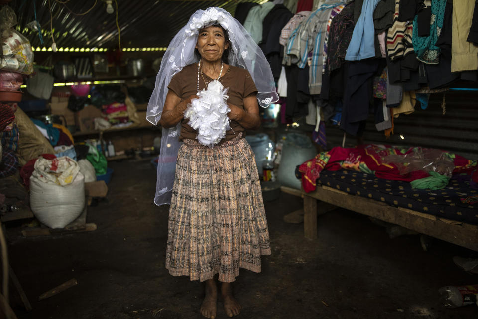 Rosario Cal, 67, poses for a photo wearing her veil and holding her bouquet, as she recalls her wedding day from this past May, in the new settlement Nuevo Queja, Guatemala, Saturday, July 10, 2021. Cal is one of a 1,000 survivors of a mudslide triggered by Hurricane Eta that buried her Guatemalan town Queja in November 2020. (AP Photo/Rodrigo Abd)