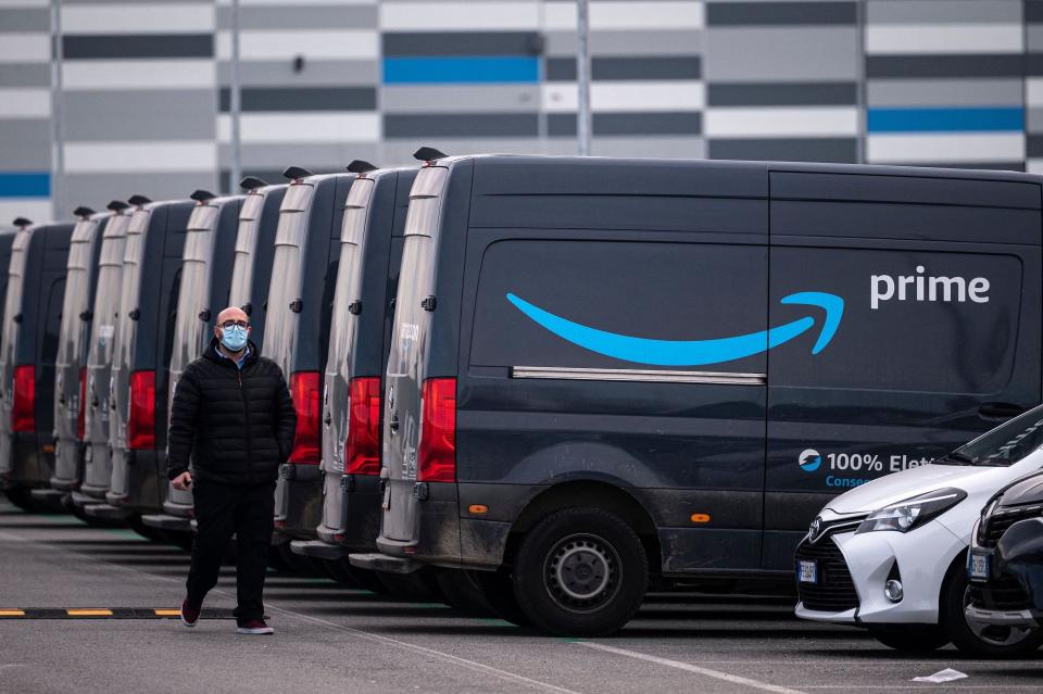 An Amazon employee walks by an Amazon Prime delivery truck in the company's premises in Brandizzo, near Turin, March 22, 2021