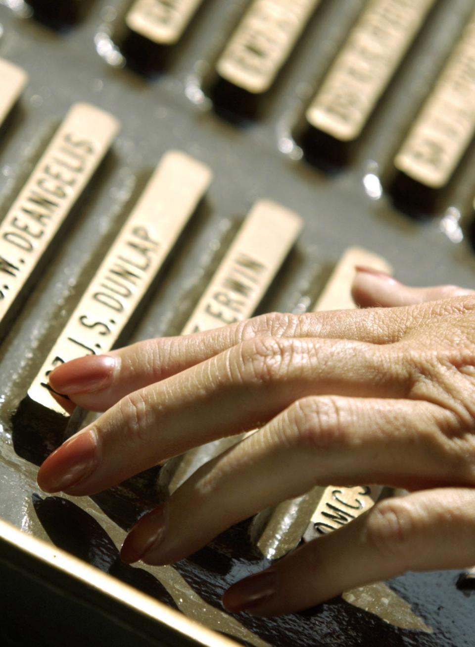 Before the start of the 2002 ceremony, a mourner runs her finger over the name of James Dunlap, one of those killed in the attack on the Stark.