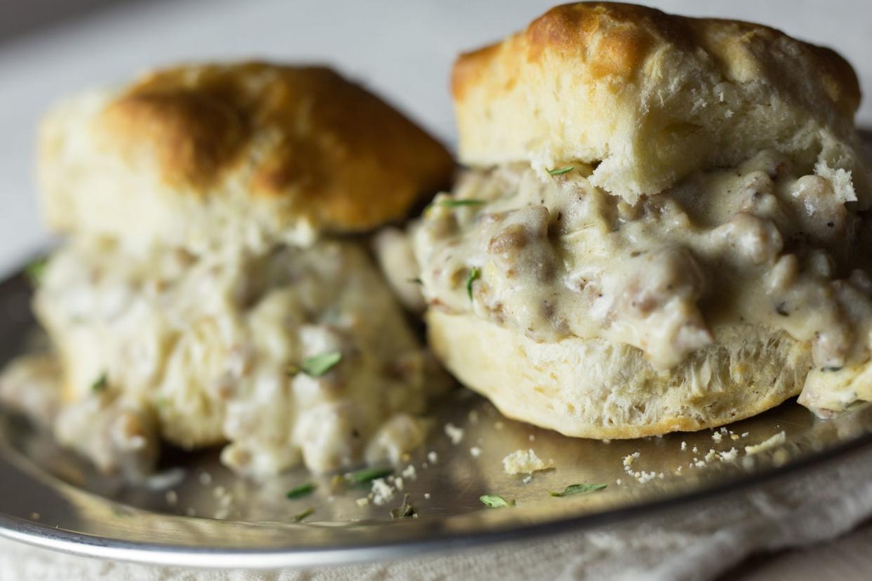 Southern style biscuits and gravy with thyme garnish on a silver platter.
