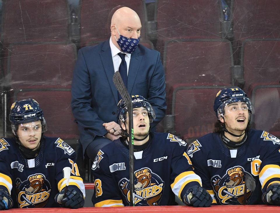 Erie Otters head coach B.J. Adams (standing) is shown before a game Jan. 13 against the Flint Firebirds at Erie Insurance Arena. Seated, from left are: centers Colby Saganiuk, Elias Cohen, and winger Daniel D'Amato.