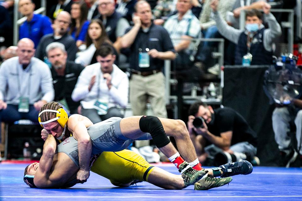 Michigan's Nick Suriano, top, wrestles Virginia Tech's Sam Latona at 125 pounds in the quarterfinals during the third session of the NCAA Division I Wrestling Championships, Friday, March 18, 2022, at Little Caesars Arena in Detroit, Mich.