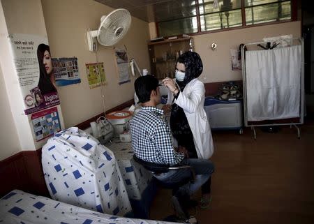 A plastic surgeon under the supervision of Afghan plastic surgeon Abdul Ghafar Ghayur, (unseen) removes facial hair from a patient's face at Aria City Hospital, in Kabul, Afghanistan August 6, 2015. REUTERS/Ahmad Masood