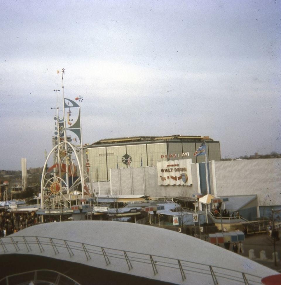 An image of a 1960s World's Fair with various rides and buildings, prominently featuring the 