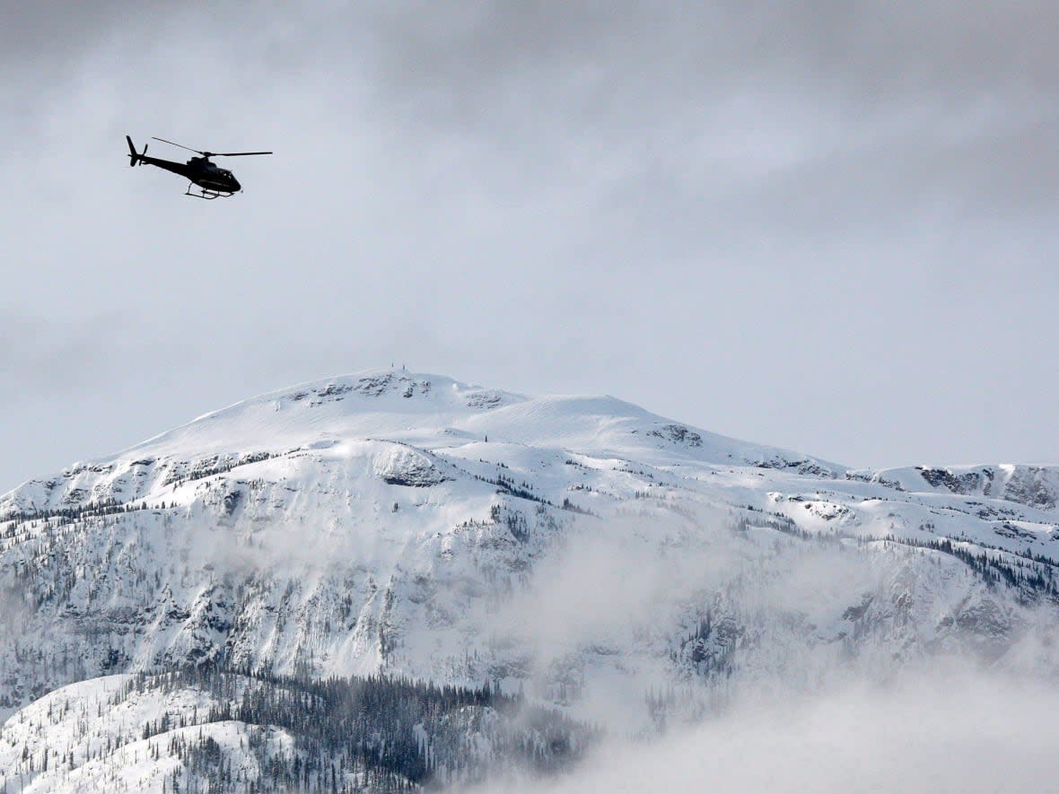 A search and rescue helicopter heads toward a deadly avalanche site near Revelstoke, B.C. (Jeff McIntosh/The Canadian Press - image credit)