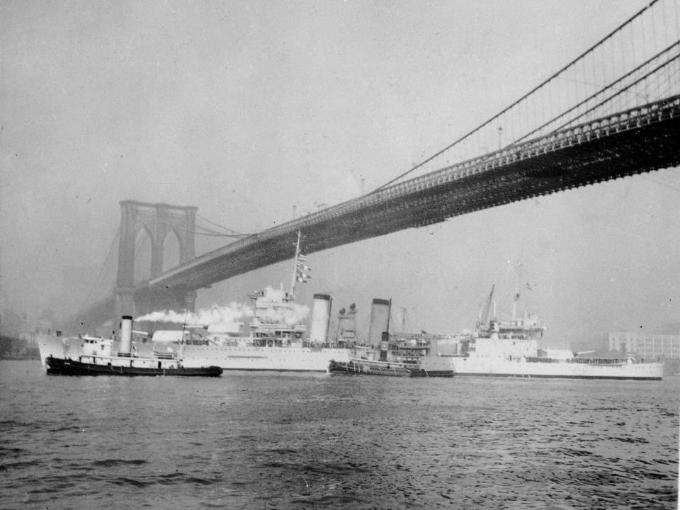 U.S.S. New Orleans passes beneath Brooklyn Bridge on its way to the Atlantic from the Brooklyn Navy Yard, April 12, 1933.