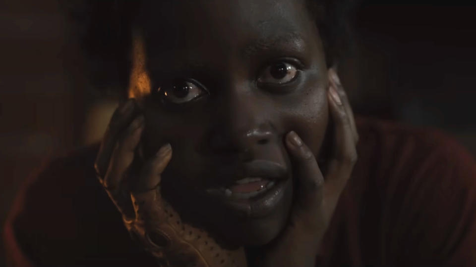 Lupita Nyong'o stares eerily ahead with her mouth open, head in her hands in Us.