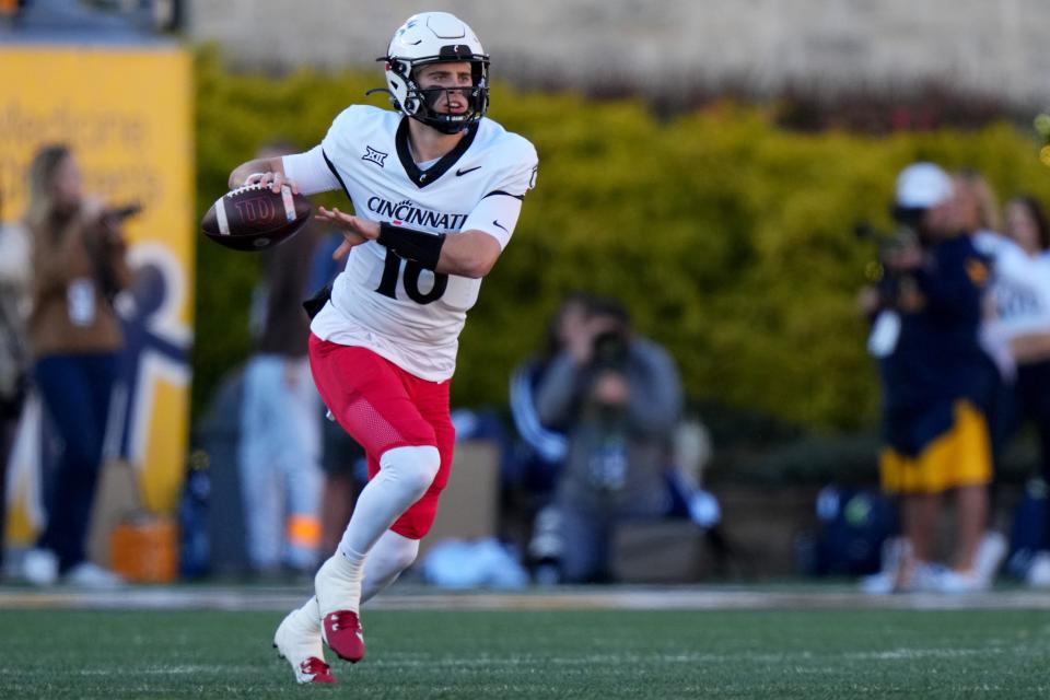 Cincinnati Bearcats quarterback Brady Lichtenberg (16) rolls out of the pocket to throw in the first quarter during an NCAA college football game between the Cincinnati Bearcats and the West Virginia Mountaineers, Saturday, Nov. 18, 2023, at Milan Puskar Stadium in Morgantown, W. Va.