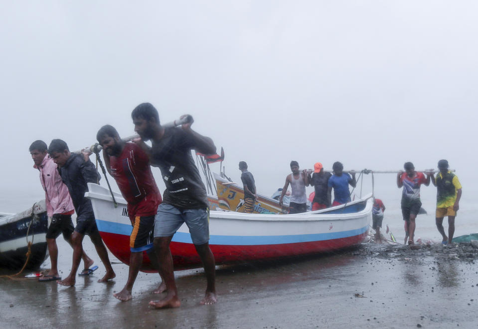 Fishermen try to move a fishing boat to a safer ground on the Arabian Sea coast in Mumbai, India, Monday, May 17, 2021. Cyclone Tauktae, roaring in the Arabian Sea was moving toward India's western coast on Monday as authorities tried to evacuate hundreds of thousands of people and suspended COVID-19 vaccinations in one state. (AP Photo/Rafiq Maqbool)