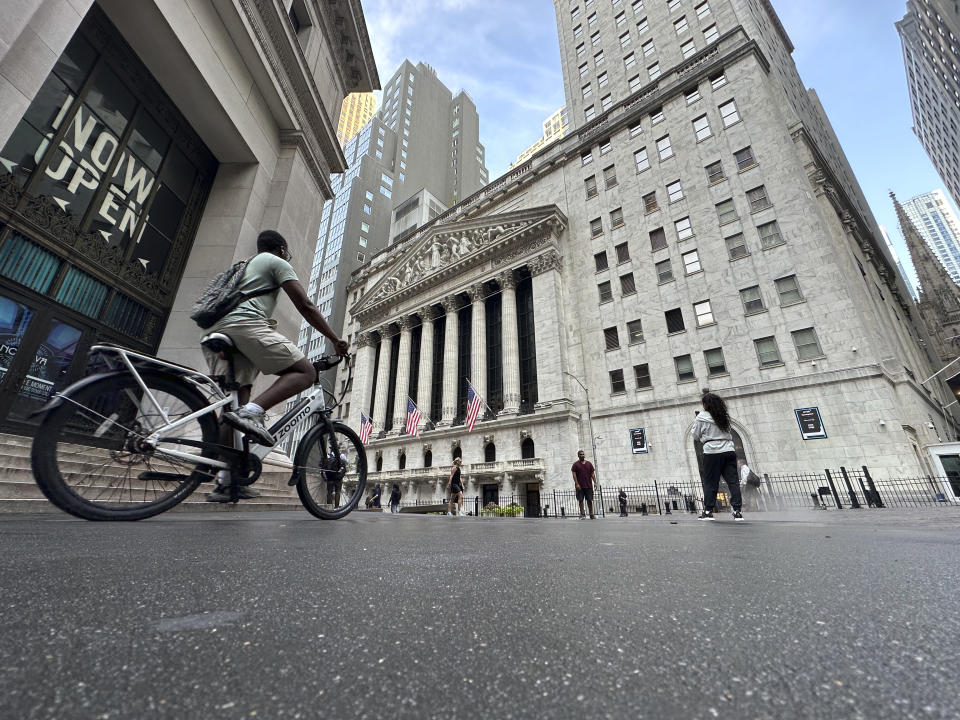 A bike rider approaches the New York Stock Exchange, rear, on Tuesday, July 9, 2024, in New York. Global shares are mostly higher, with Japan's benchmark Nikkei 225 jumping 2% to finish at another record high. (AP Photo/Peter Morgan)