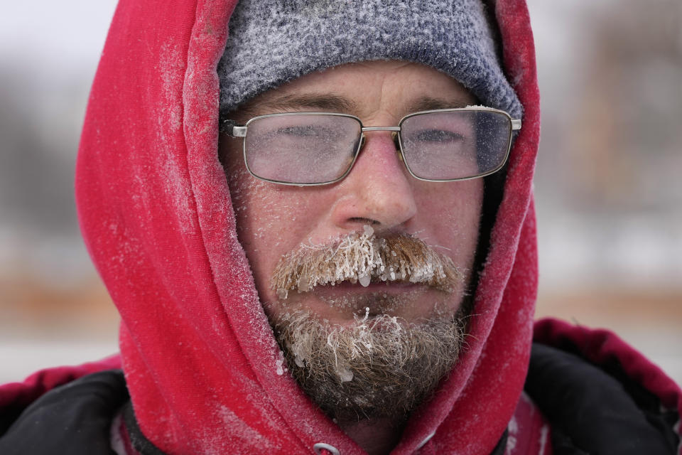 Mark Sorter's face is seen covered in snow and ice as he clears snow from a downtown ice skating rink, Friday, Dec. 23, 2022, in Des Moines, Iowa. (AP Photo/Charlie Neibergall)