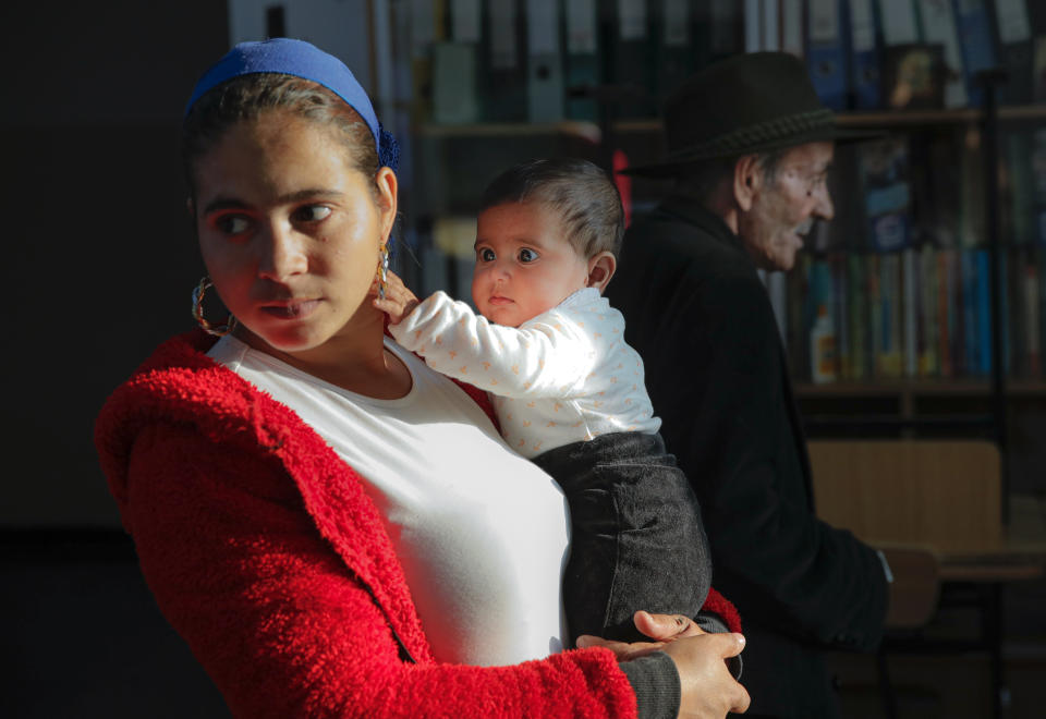 Baby Sonia grabs her mother's earring at a polling station in Sintesti, Romania, Sunday, Nov. 10, 2019. Romania held a presidential election Sunday after a lackluster campaign that has been overshadowed by the country's political crisis, which saw a minority government installed just a few days ago. (AP Photo/Vadim Ghirda)