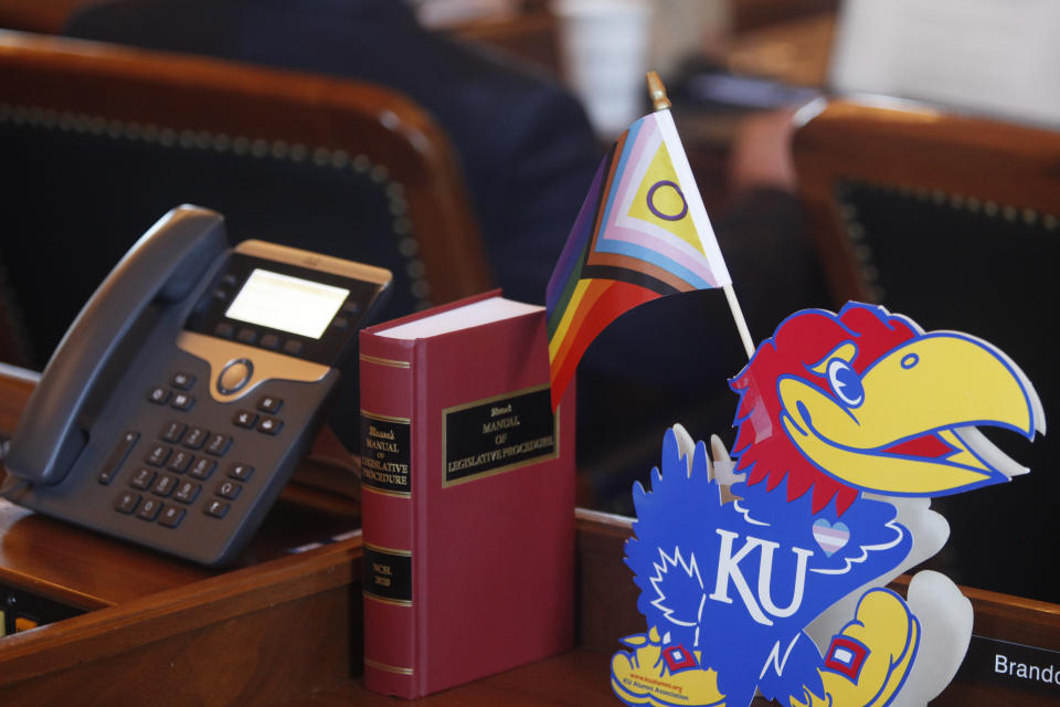 A flag celebrating LGBTQ rights sits on the desk of Kansas state Rep. Brandon Woodard, D-Lenexa, in the Kansas House, Thursday, April 6, 2023, in Topeka, Kan. Woodard, a University of Kansas graduate, is among three LGBTQ lawmakers in Kansas and a vocal opponent of measures to roll back transgender rights. (AP Photo/John Hanna)