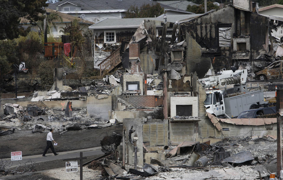 FILE - In this Sept. 13, 2010, file photo, a man walks past the remains of homes damaged from a fire caused by an explosion in a mostly residential area in San Bruno, Calif. Pacific Gas & Electric Co. pleaded not guilty Monday, April 21, 2014, to a dozen felony charges stemming from alleged safety violations in a deadly 2010 natural gas pipeline explosion that leveled a suburban neighborhood in the San Francisco Bay Area. As survivors of the blast looked on, attorneys for California's largest utility entered the plea in federal court in San Francisco to 12 felony violations of federal pipeline safety laws. (AP Photo/Jeff Chiu, File)