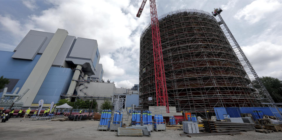 A vast thermal tank, right, to store hot water is pictured in Berlin, Germany, Thursday, June 30, 2022. Power provider Vattenfall unveiled a new facility in Berlin on Thursday that turns solar and wind energy into heat, which can be stored in a vast thermal tank and released into the German capital's grid as needed, smoothing out the fluctuating supply problem of renewables. (AP Photo/Michael Sohn)