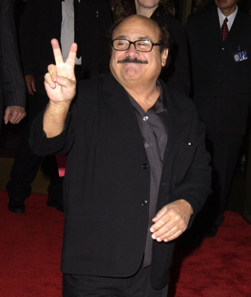 he's got a mustache and glasses wearing a suit