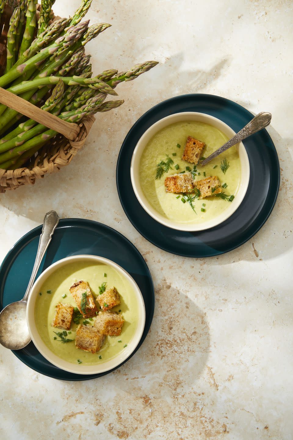 bowls of cream of asparagus soup with parmesan croutons with spoons