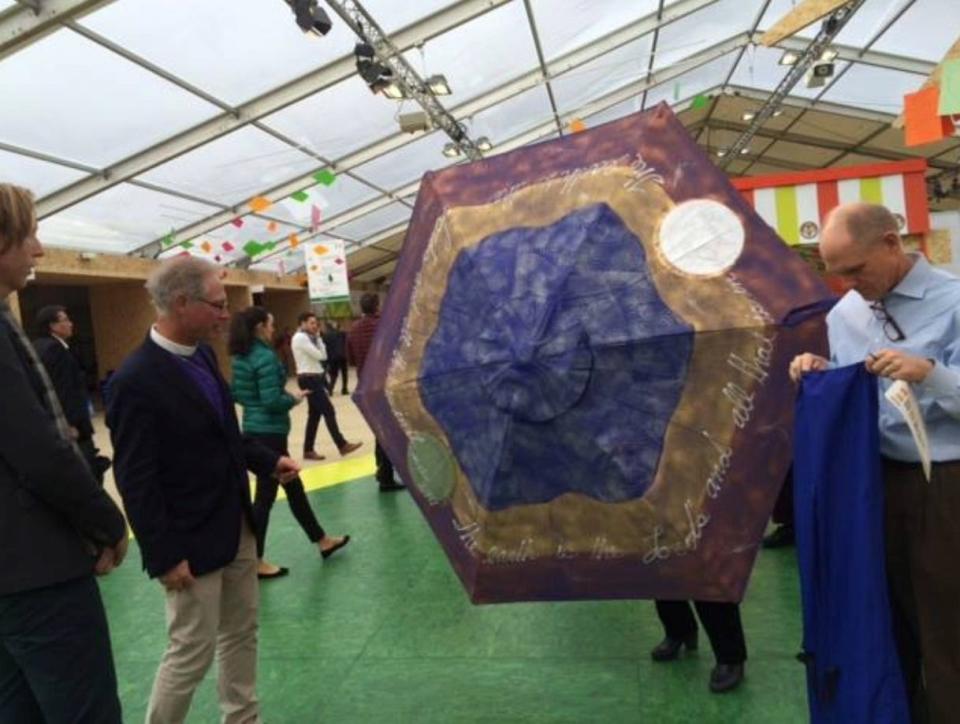 California Bishop Marc Andrus, at left wearing glasses, watches an umbrella being raised as part of a “pop-up” worship service in a public place during the 2022 United Nations climate change conference in Paris. Andrus was an Episcopal leader working on behalf of an agreement to reduce carbon emissions.