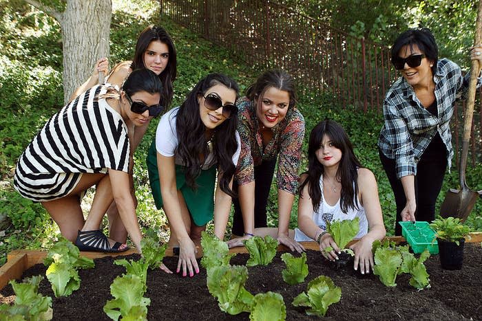 Kris and her daughters posing behind a garden of lettuce