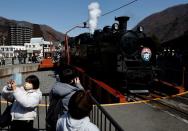 Visitors take photos of the steam-locomotive-powered sightseeing train SL Taiju at Kinugawa Onsen Station in Nikko