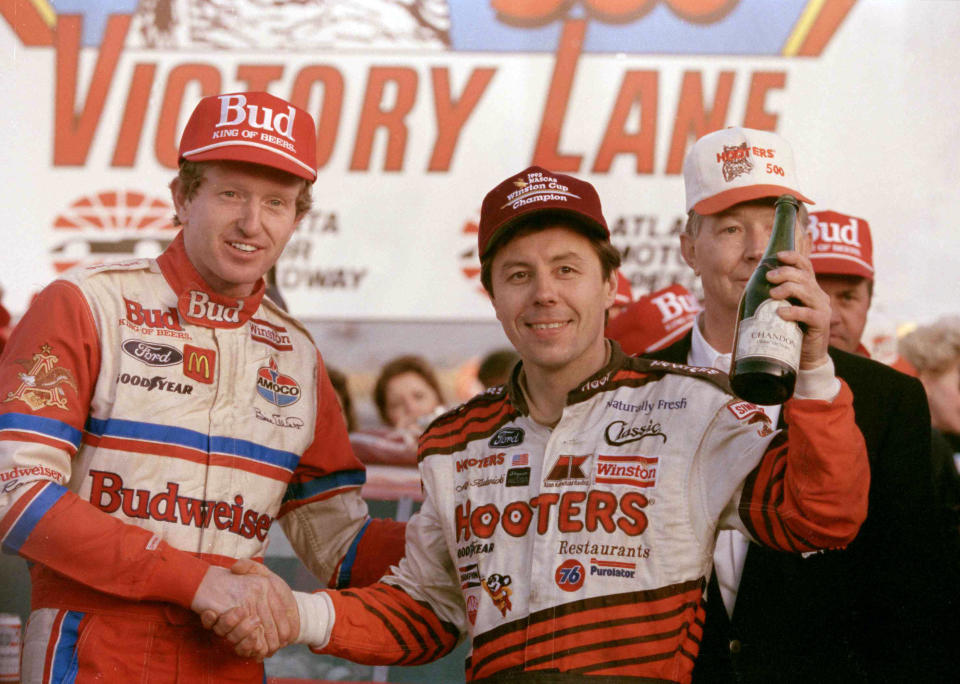 FILE - Hooters 500 winner Bill Elliott, left, and NASCAR Winston Cup champion Alan Kulwicki celebrate in Victory Lane following the Hooters 500 at Atlanta Motor Speedway in Hampton, Ga., in this Nov. 15, 1992, file photo. Chase Elliott will honor the late Alan Kulwicki by racing the same Hooters paint scheme that was on Kulwicki’s car in the 1992 season finale at Atlanta Motor Speedway when Kulwicki beat Bill Elliott for the Winston Cup title. Chase Elliott will run the paint scheme at Darlington Raceway on May 9, 2021. (AP Photo/John Bazemore, File)