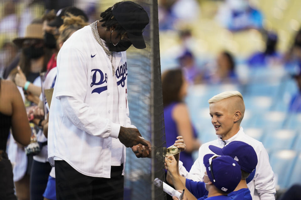 Los Angeles Rams cornerback Jalen Ramsey signs dollar bills for fans before he threw out the first pitch at a baseball game between the Milwaukee Brewers and the Los Angeles Dodgers Saturday, Oct. 2, 2021, in Los Angeles. (AP Photo/Ashley Landis)