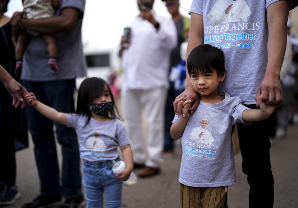 Leo Ignacio holds the hand of his four-year-old son Lucas as they wait in line to to enter and see Pope Francis deliver a holy mass at Commonwealth Stadium during his papal visit across Canada in Edmonton on Tuesday, July 26, 2022. (Nathan Denette /The Canadian Press via AP)