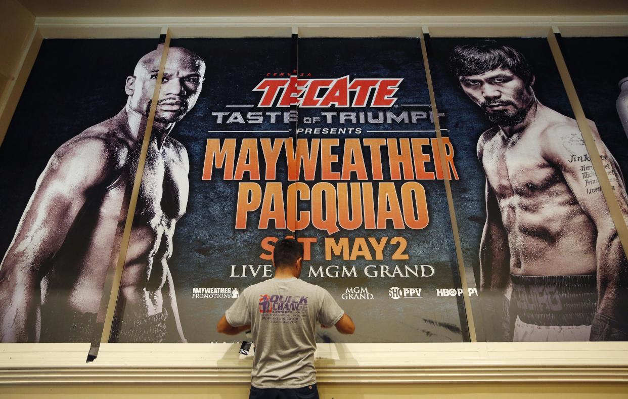En esta foto del viernes 24 de abril de 2015, un hombre instala un cartel publicitario para la pelea entre Floyd Mayweather y Manny Pacquiao en el hotel y casino MGM Grand de Las Vegas (AP Foto/John Locher)