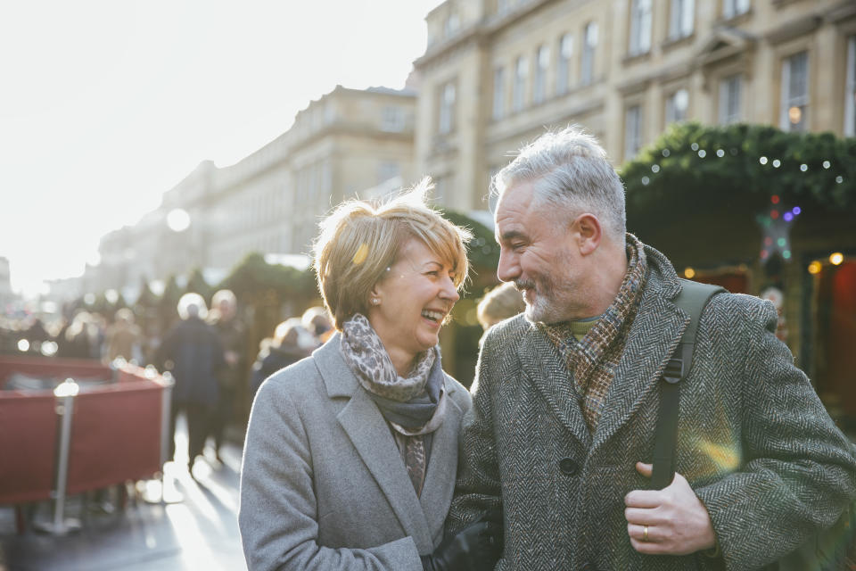 A mature married couple are walking through a Christmas market together.