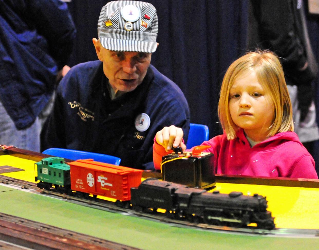 Tom Staszak, of the NEW “O” Gaugers train club, offers advice to Kimberlynn Gumm, Appleton, as she races model trains during the Titletown Train Show.