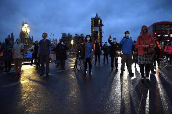 People wearing face masks and holding lanterns attend a vigil for the victims of the coronavirus on Westminster Bridge on 3 July 2020 in London, England (Photo by Chris J Ratcliffe/Getty Images)