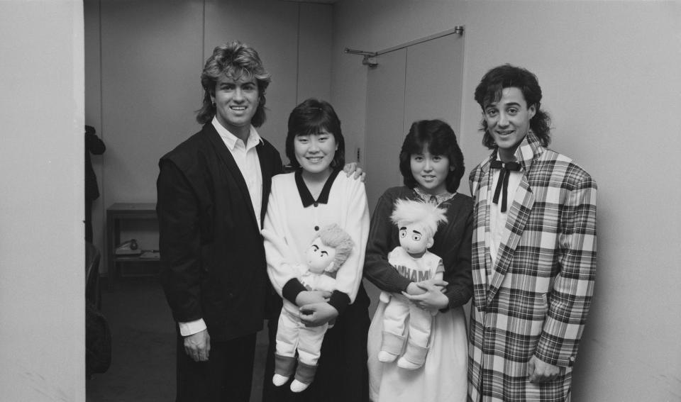 George Michael and Andrew Ridgeley with two teenage fans, each carrying a Wham! doll, during the pop duo's 1985 world tour. (Michael Putland/Getty Images)