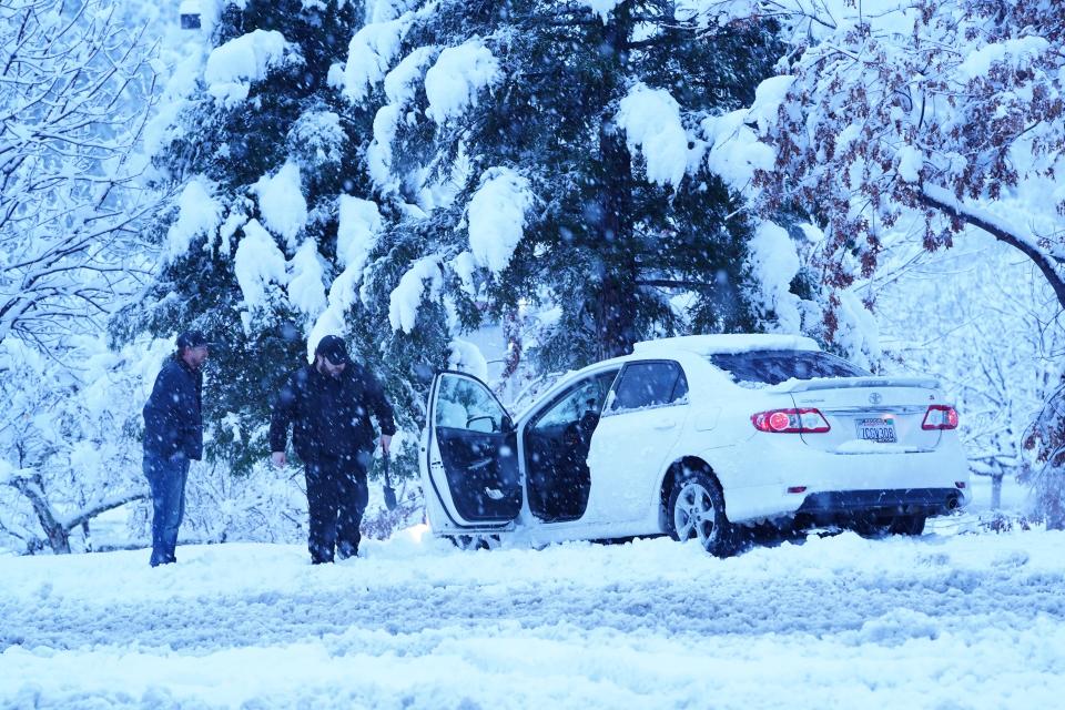 A stranded motorist tries to dig his car out of the snow after spinning out on Hilltop Drive at Lake Boulevard early on Friday morning, Feb. 24, 2023.