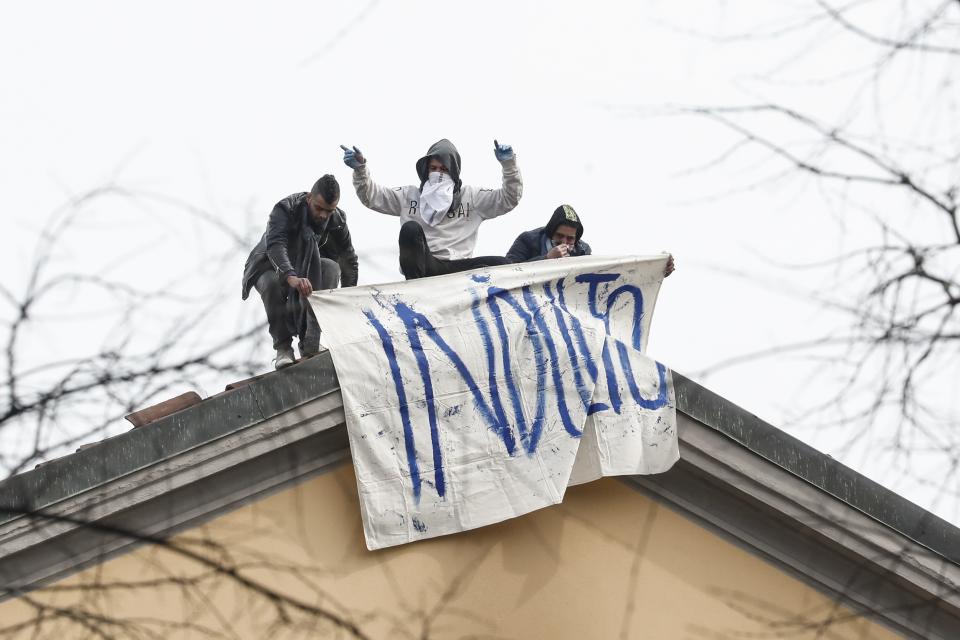 Inmates unfold a banner reading in Italian Pardon as they stage a protest against new rules, including the suspension of relatives' visits, to cope with coronavirus emergency, on the roof of the San Vittore prison in Milan, Italy, Monday, March 9, 2020. Italy took a page from China's playbook Sunday, attempting to lock down 16 million people — more than a quarter of its population — for nearly a month to halt the relentless march of the new coronavirus across Europe. (AP Photo/Antonio Calanni)