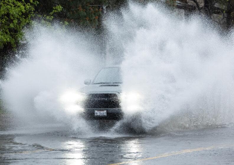 NORTH HOLLYWOOD, CA- MARCH 30: A car splashes through a flooded Vanowen Street in North Hollywood, CA on Saturday, March 30, 2024 during a rainy Easter weekend. (Myung J. Chun / Los Angeles Times)