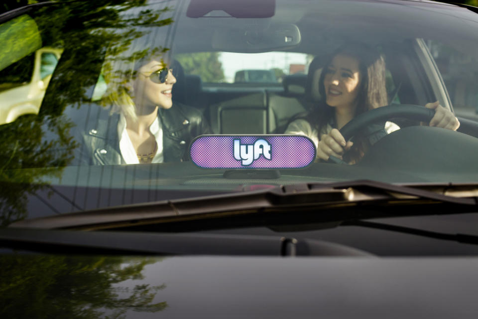 Two women chat in the front of a Lyft car.